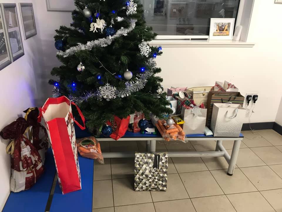 Decorated Christmas tree beside a table with various wrapped gifts and bags