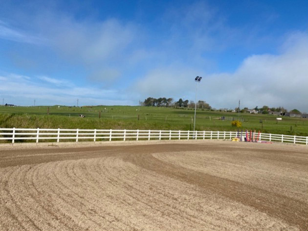 Horse racing track with white fence, green field, and blue sky with light clouds