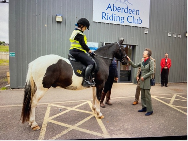 Rider on a horse interacting with a person outside Aberdeen Riding Club