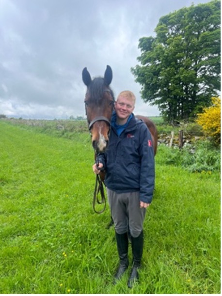 Person standing with a horse in a green field